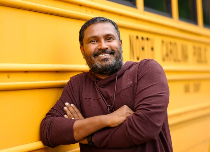 Bus driver leaning on the side of a bus at Wake County Public School System.