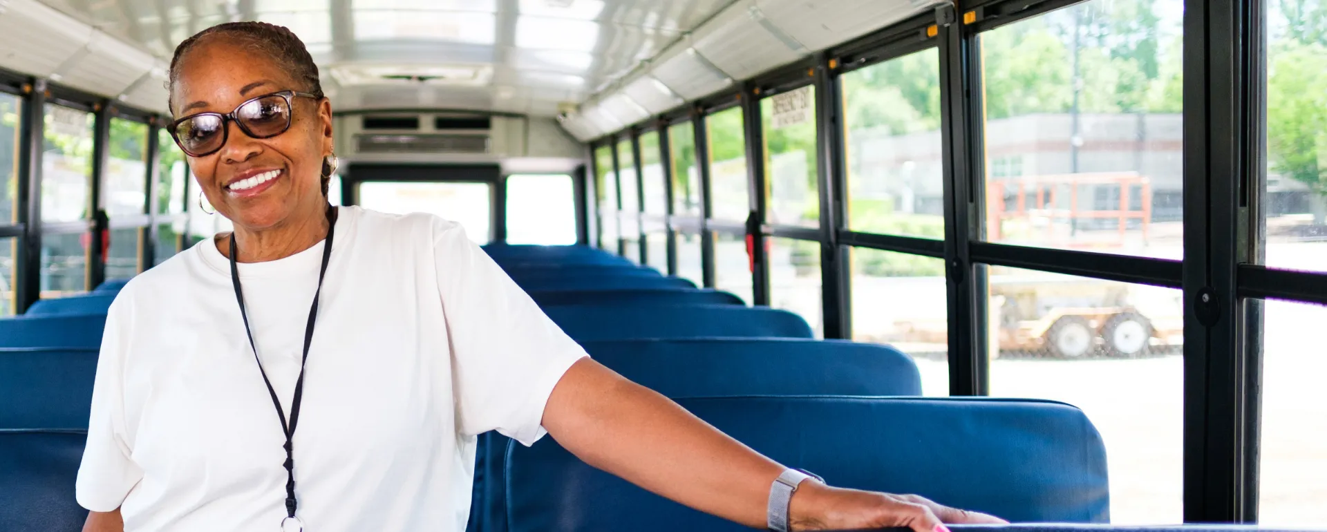 A bus safety assistant smiling and standing on a bus.