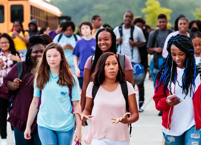 Students walking away from a bus at Wake County.