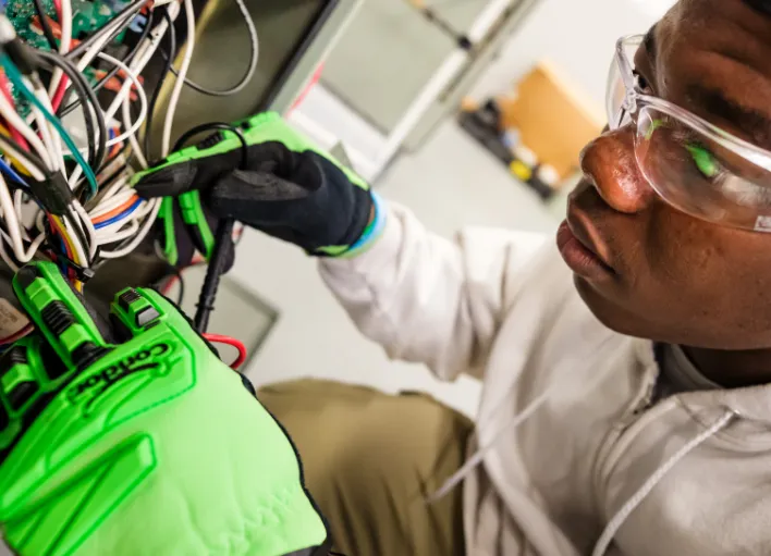 An HVAC technician working with cables while wearing protective gloves.