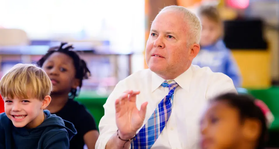 A principal sitting with a kindergarten class.