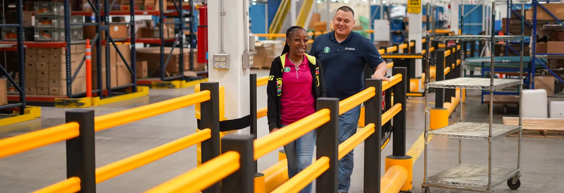 Smiling Yamaha employees walking at a warehouse.