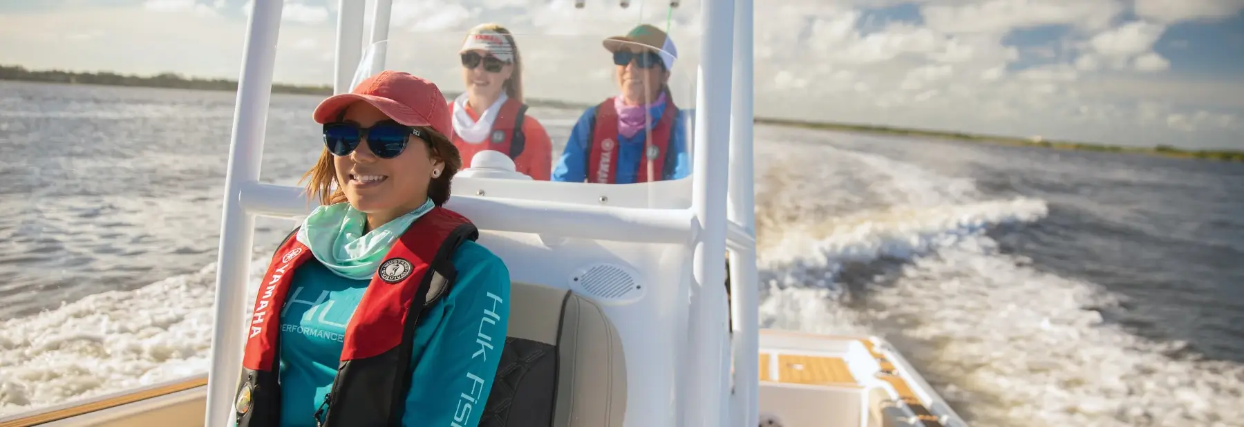 Three people enjoying a sunny day on the lake in a Yamaha boat.