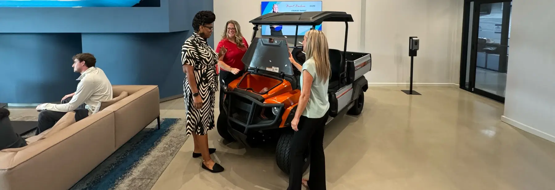 A Yamaha salesperson showing a golf car product to customers.