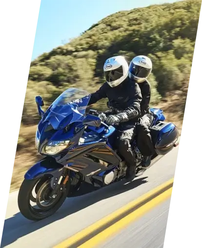 Two people riding a bright blue Yamaha motorcycle.