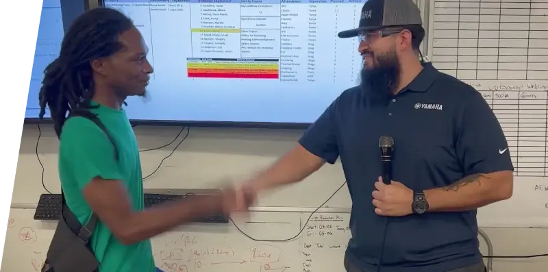 Two employees shaking hands at a recognition award presentation.
