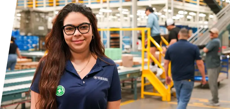 A smiling Yamaha employee on the manufacturing floor.