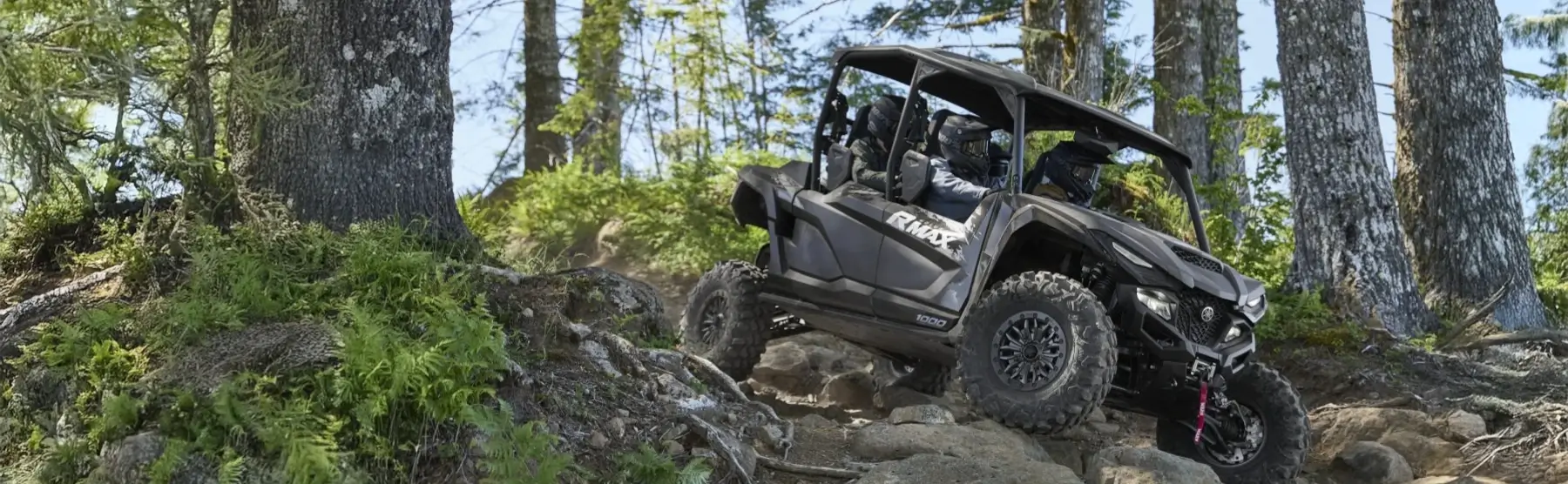 A Yamaha Wolverine side-by-side offroad vehicle in a forest.