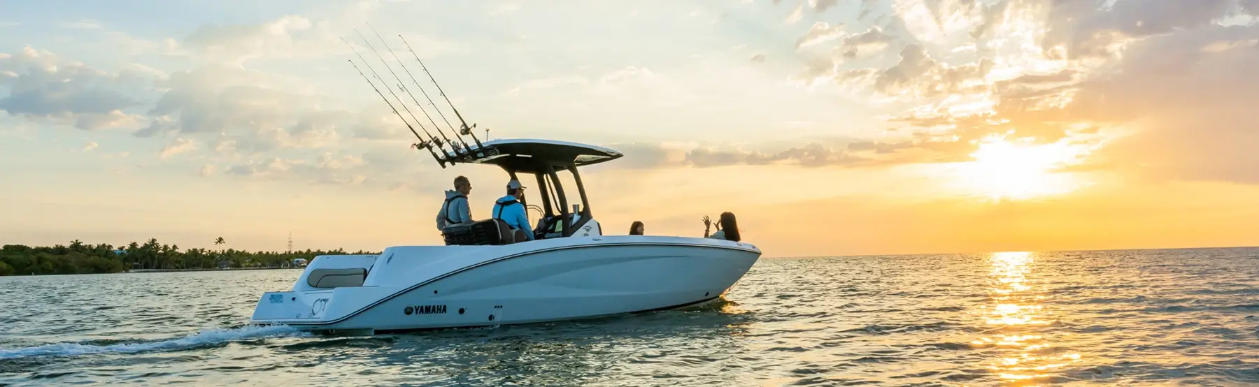 Four people watching the sunrise over the water in a Yamaha fishing boat.