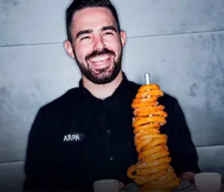 A happy food runner holding a stem of onion rings.