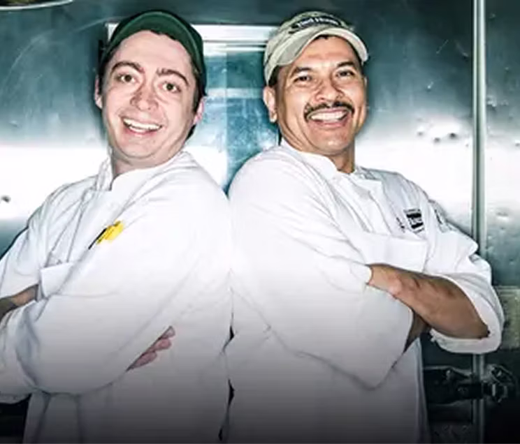 Two Yard House cooks standing back-to-back with their arms crossed, smiling.
