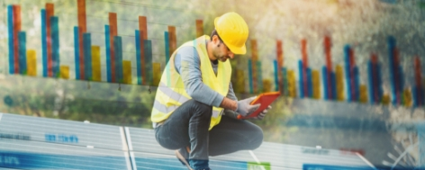 A technician kneeling down and looking at a tablet.