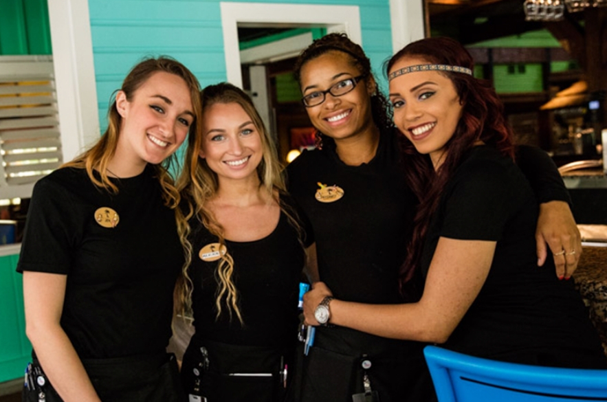 A Bahama Breeze employee carrying plates and smiling
