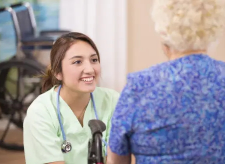 A Bethesda employee smiling as she talks to an elderly patient