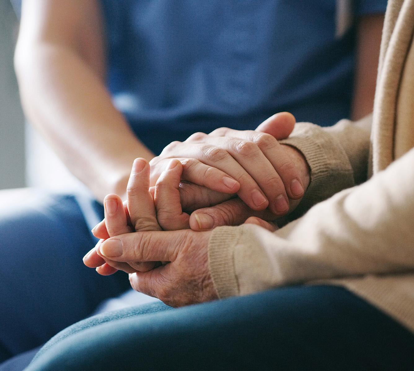 A nurse holding the hand of an elderly patient.