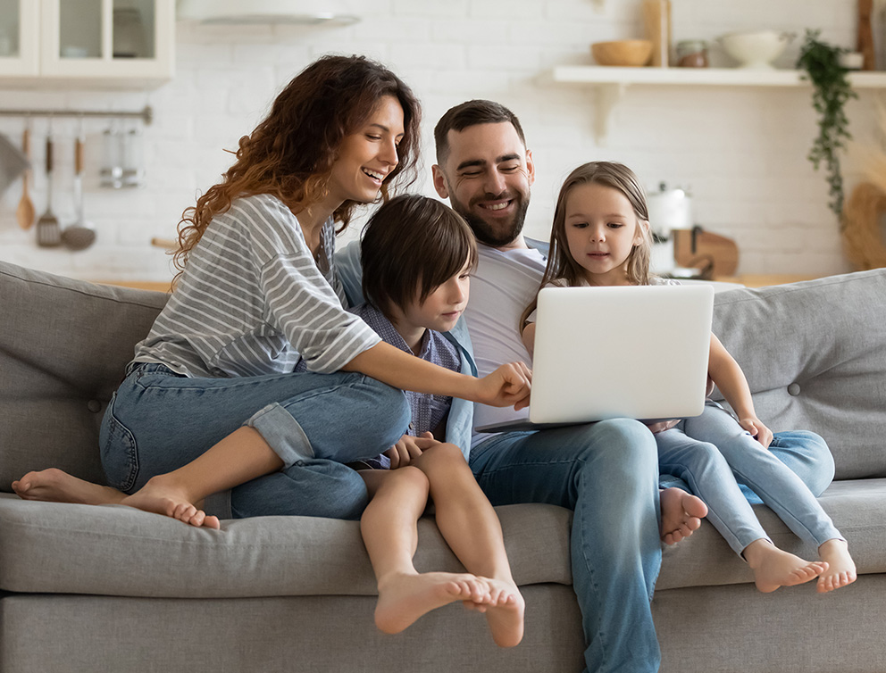 A family smiling as they look at a laptop.