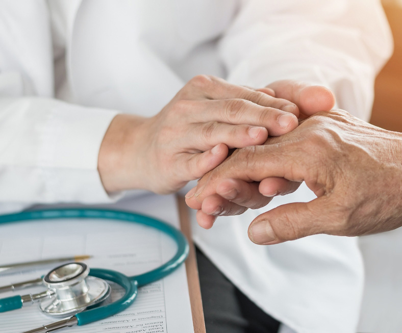 A doctor holding the hand of an elderly patient.