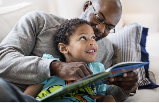  	An adult and child reading a book together.