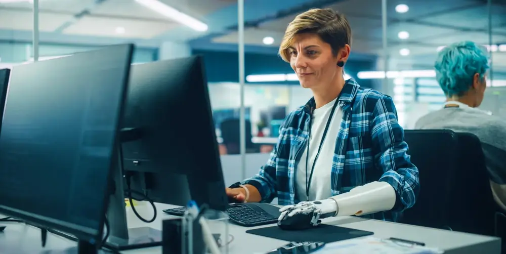 An employee with a prosthetic arm working at a computer.