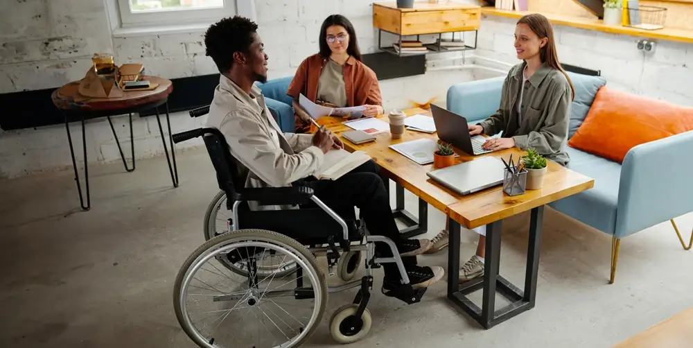 An employee in a wheelchair discussing work with a colleague.