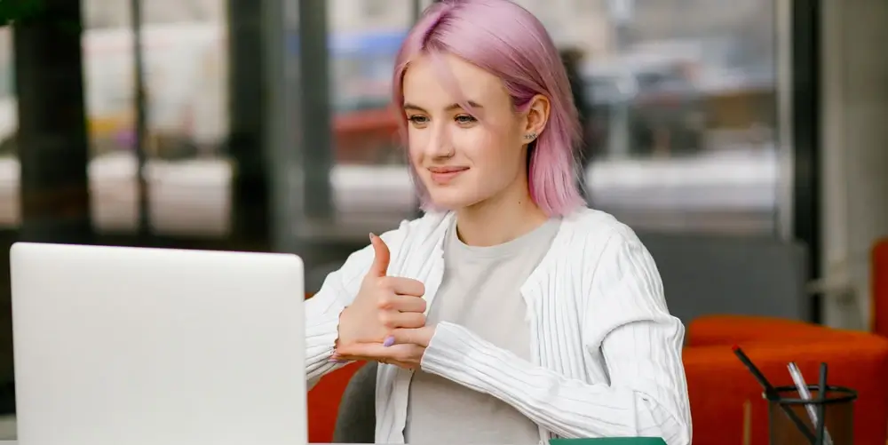 An employee on a video call signing â€œhelpâ€ in American Sign Language.