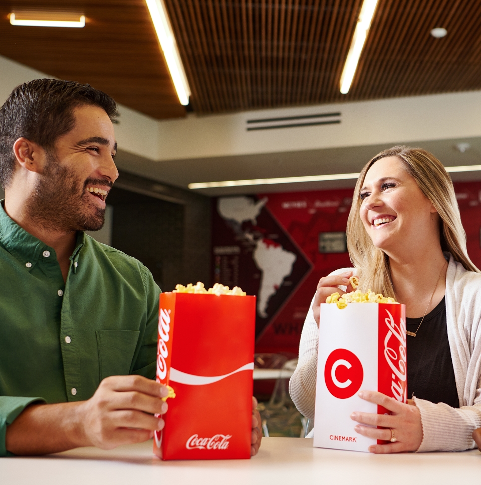 Cinemark employees laughing while eating popcorn.