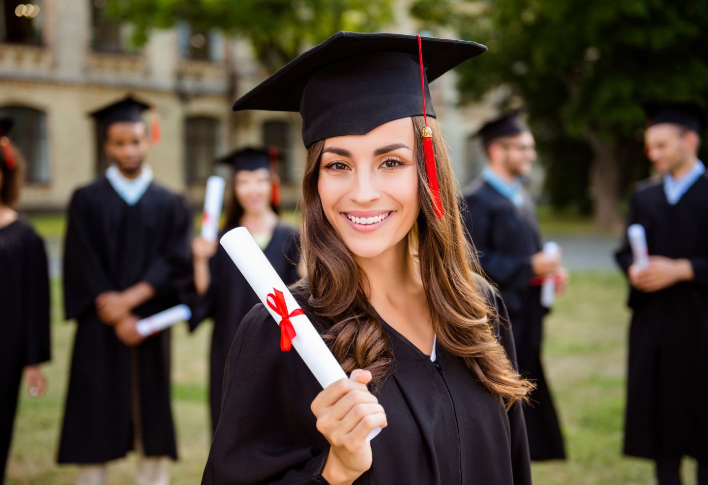 Woman wearing graduation regalia and holding a diploma.