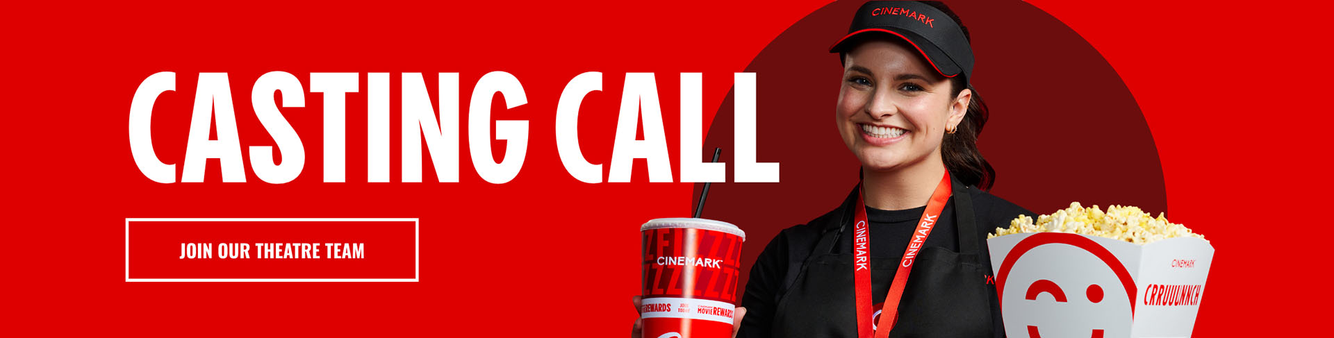 Cinemark employee holding a Cinemark soda and popcorn.
