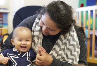 An educator holding and instructing a baby.