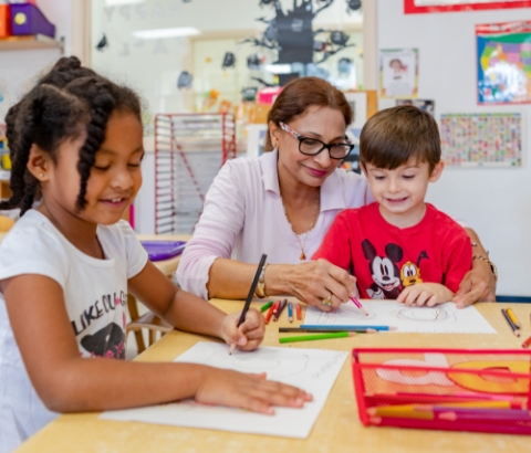 A little boy learning about plants and a guide instructing two students with writing.