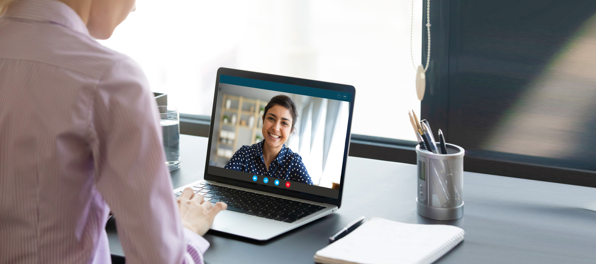 A telehealth counselor conducting a virtual meeting session with her client smiling on screen.