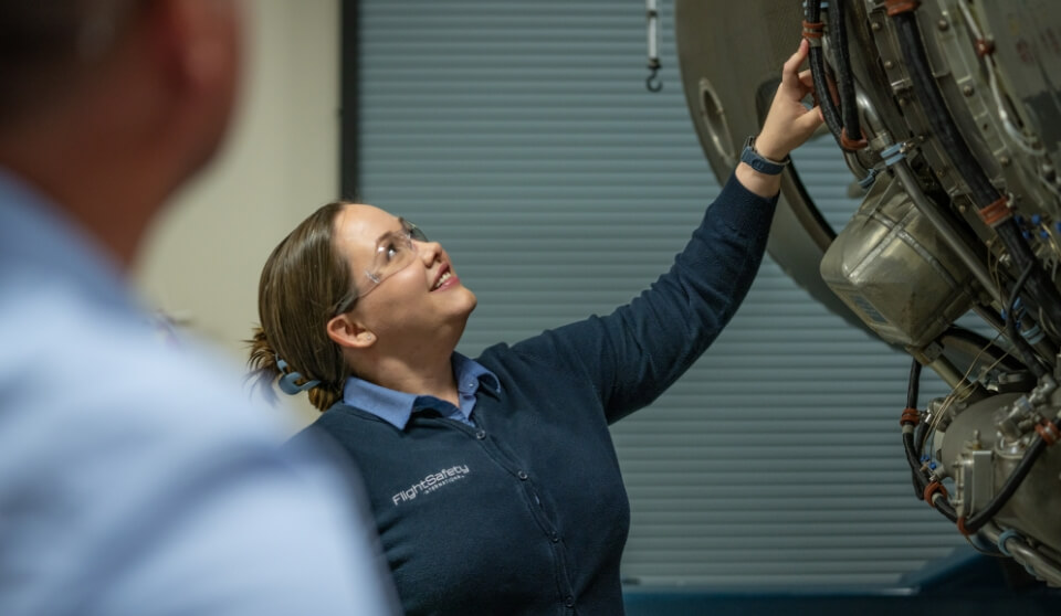 An FSI employee smiling while looking at simulation equipment.