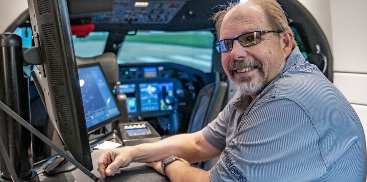 An FSI employee smiling in an FSI simulator.