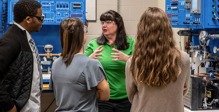 A female Ivy Tech faculty member teaches three students in a technology lab.