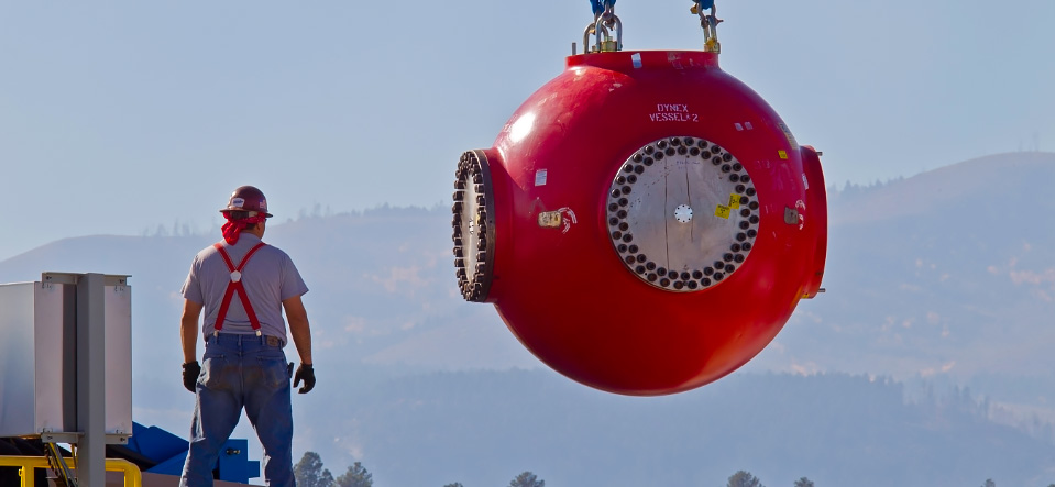 LANL engineer in safety goggles inspecting machinery