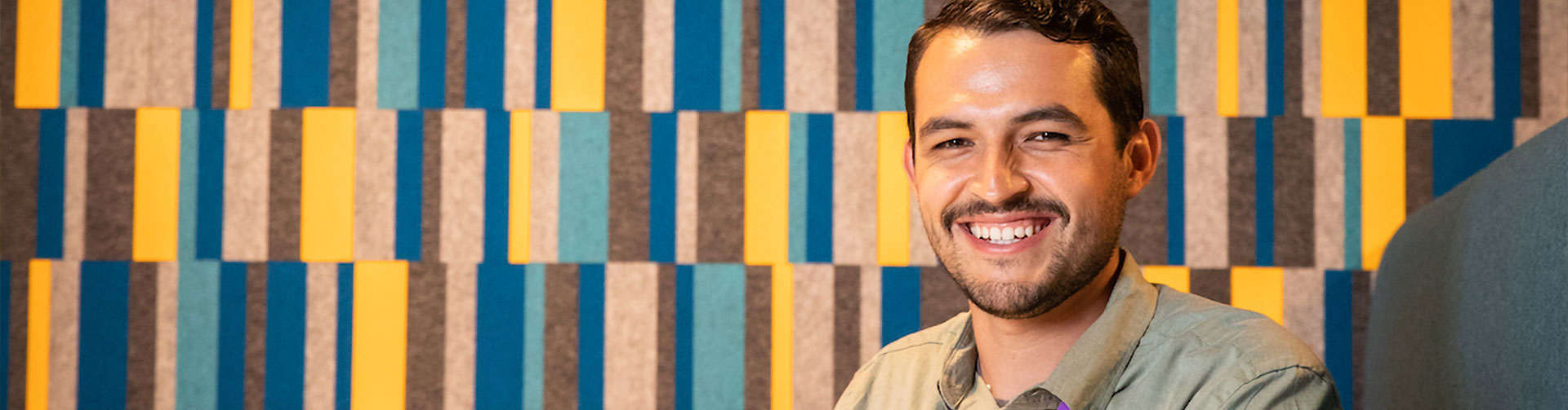 Smiling LANL employee in front of a paneled wall