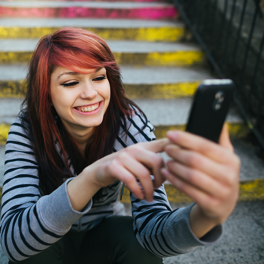 Person smiling as they use their mobile phone.