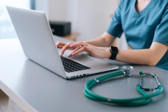 Healthcare professional typing on a laptop