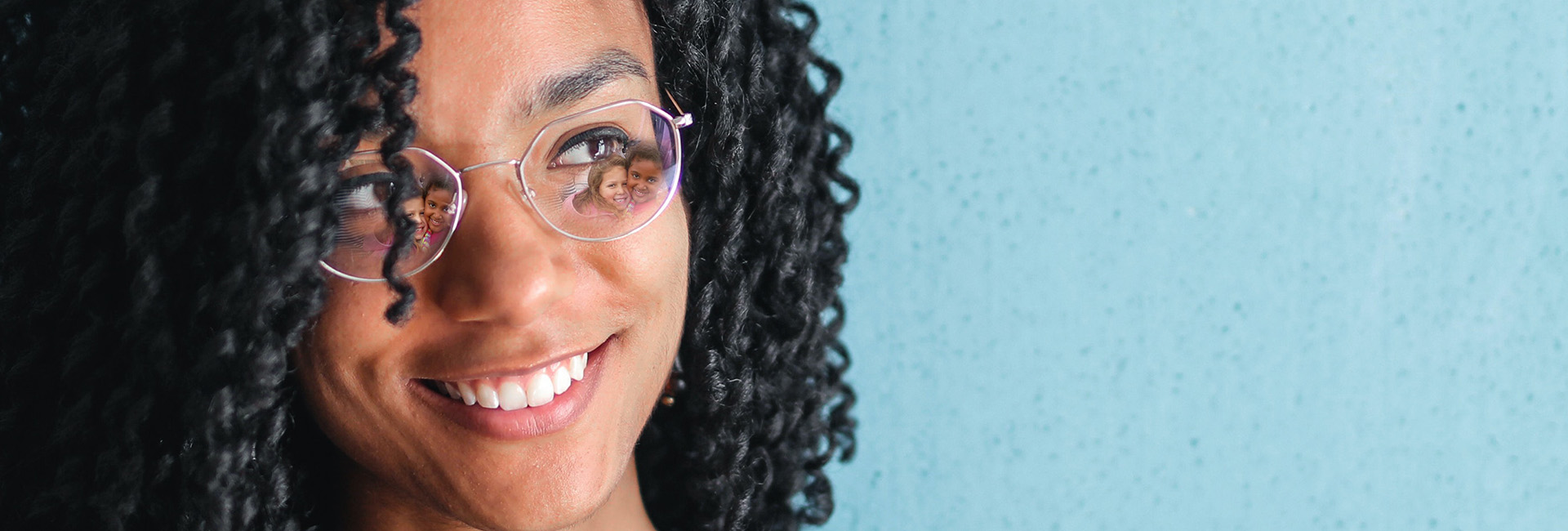 Smiling woman wearing glasses with children's reflections