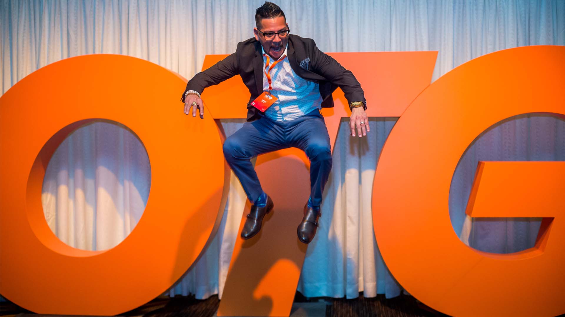 Jubilant employee jumps in front of large letters spelling out OTG