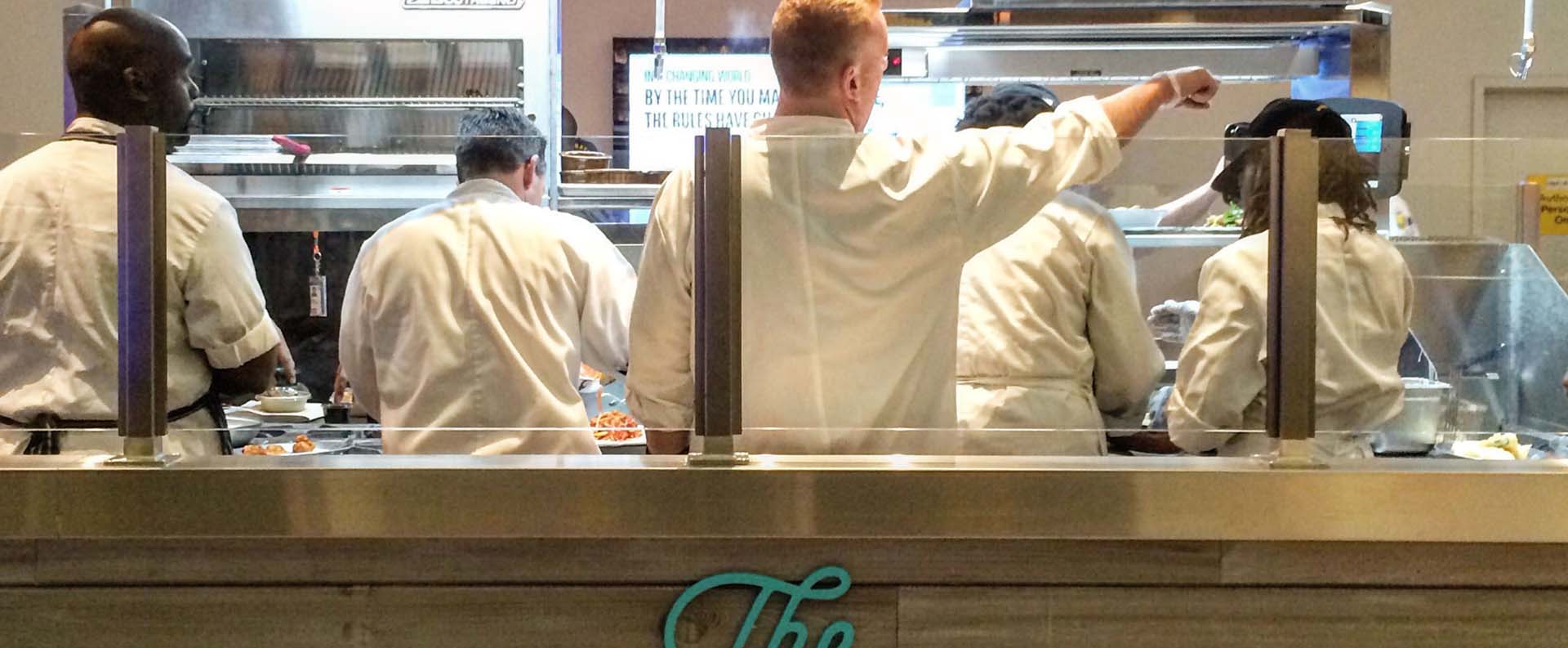 Staff at an OTG airport restaurant work the food prep line