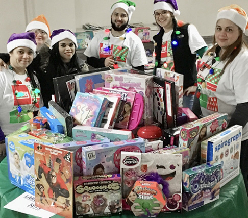 Empleados de Oatey sonriendo con donaciones de regalos navide&ntilde;os para obras de caridad.