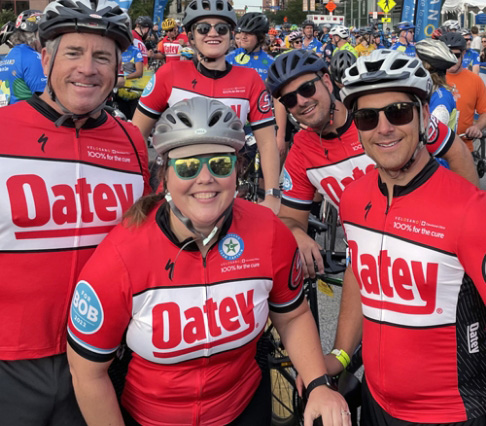 Empleados de Oatey sonriendo en un evento de ciclismo.
