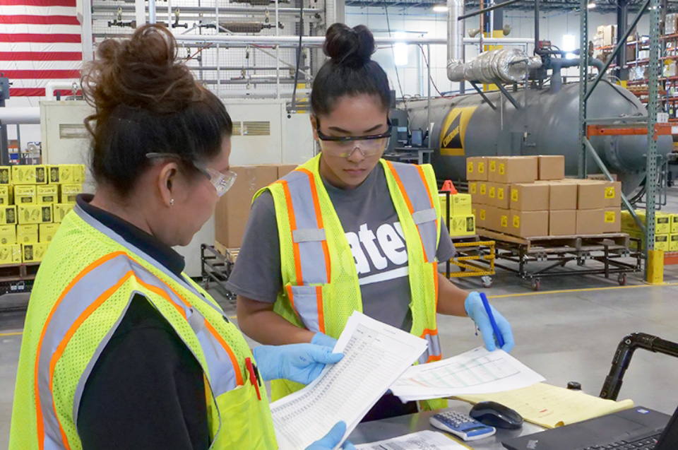 Oatey employees discussing work documents.