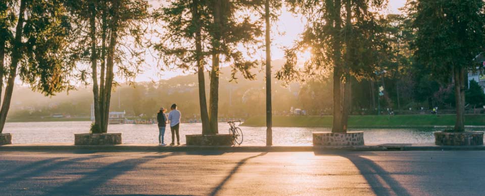 Two people looking at a sunset over a lake.