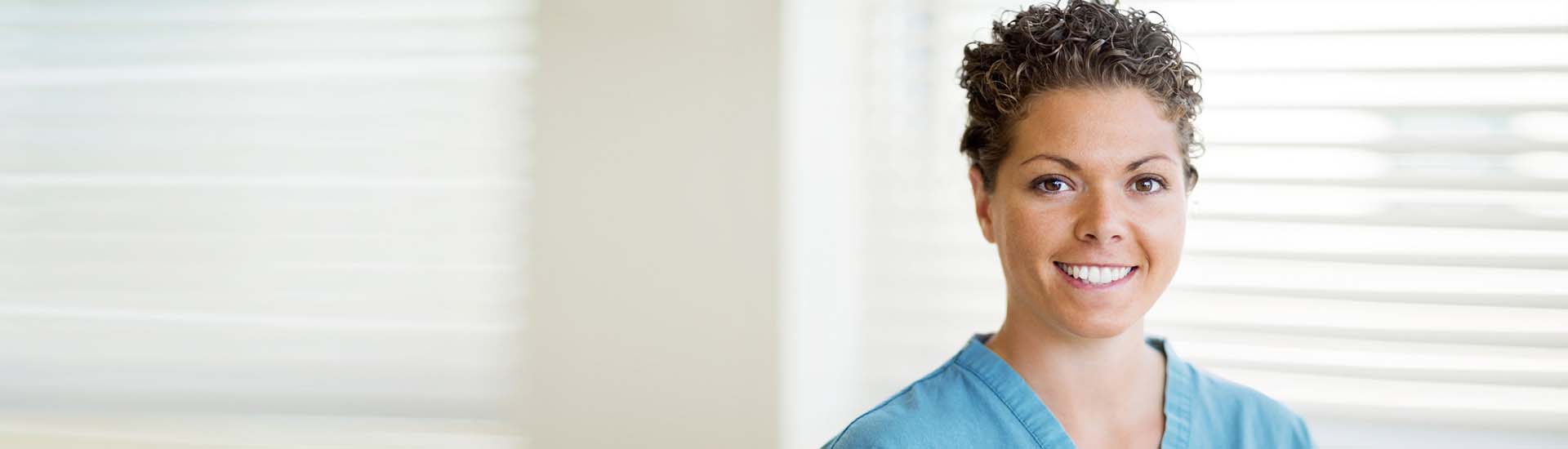 A young, female Ohio Living nurse pauses to smile during her busy workday.