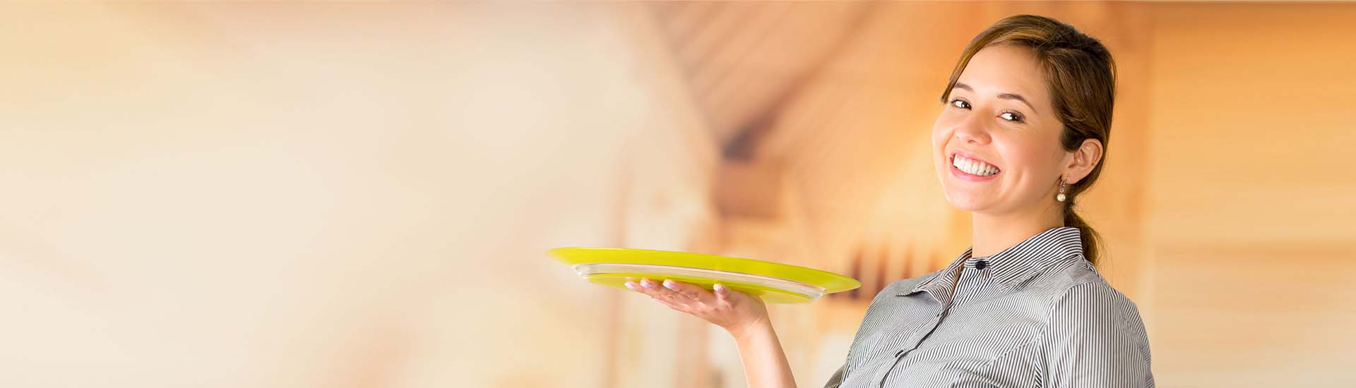 A young, female servers smiles as she delivers a meal.