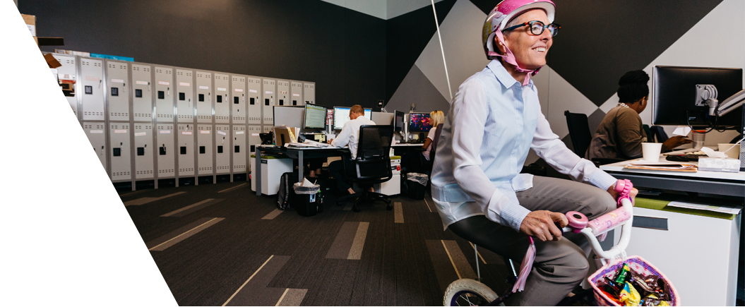  	PatientPoint employee riding a childrenâ€™s bicycle in an office.