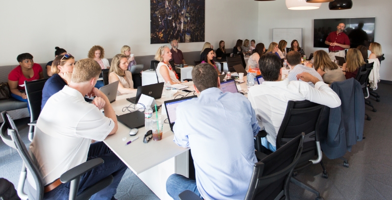  	A large group of PatientPoint employees sitting at a conference room table.