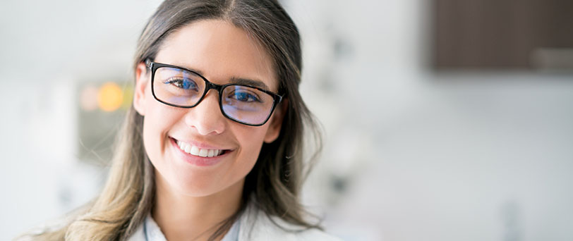A smiling female specialist in glasses and a white coat